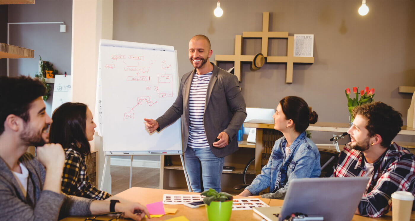 A male facilitator guides his team of four business professions through the facilitative method.